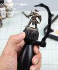 Precision Miniature Painting Handle With Stabilizer Bar And Magnetic Base held by hand showing 360 degree rotation with figure.