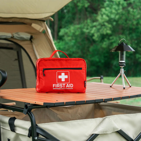 Rhino Rescue 240-Piece All-Purpose First Aid Kit, red, on camping table beside lantern.