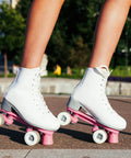Woman skating outdoors wearing white boots with 32 x 58mm PU Roller Skate Wheels With Bearings, 4 Pack Quad Replacement, 82A hardness.