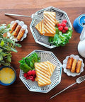 Two plates with grilled sandwiches, raspberries, lettuce, and snacks, showcasing Durable Aluminum Grilled Sandwich Maker For Stovetop Use.