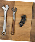 Wooden puzzle toy with two metal wrenches and black rubber grommets on a wooden surface