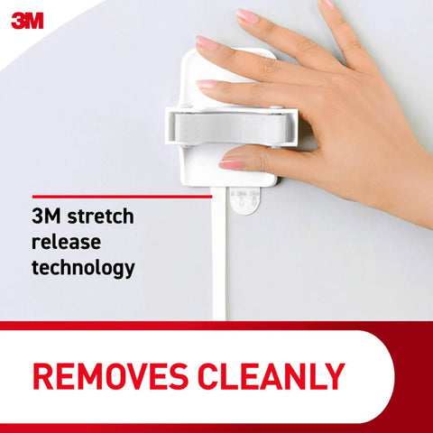 Damage Free Broom And Mop Holder Wall Mount With Three Grippers And Six Adhesive Strips Keeps Brooms And Mops Right Where You Need Them In Kitchen Laundry Room Or Closet Holds Up To Four Pounds shown with hand demonstrating removal on wall.