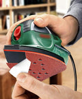 Person applying 12-hole sanding pad to detail sander, highlighting No Fuss Mouse Sander Sanding Pads Set, 50 Pack With 60 80 120 150 And 220 Grits.