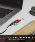 Mycro Keychain Flashlight 400 Lumen Rechargeable EDC Light connected to laptop via USB for charging next to notebook and sunglasses.