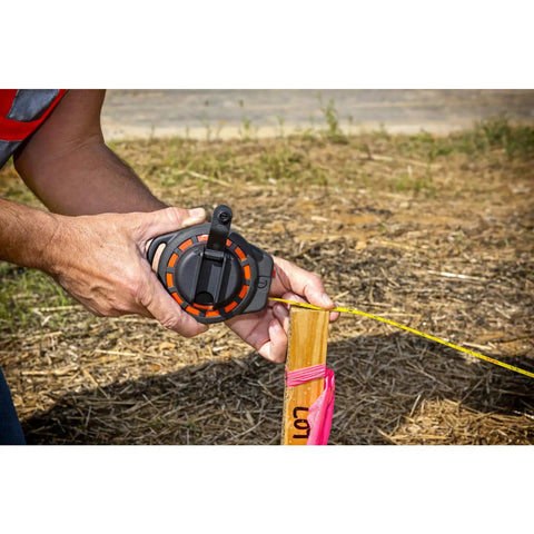 Worker using Three Eighths Inch By Fifty Foot Steel Construction Long Tape Measure With Three To One Gear outdoors.