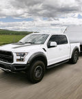 White truck towing a trailer on a highway using Weight Distribution Hitch With Tension Chain System For Easy Hitching And Anti Bounce Sway Control, 2 Inch Shank, Eight Inch Drop, 2 Five Sixteenths Inch Ball, 14K GTWR, Brackets Three To Six Inches, Tow Gear.