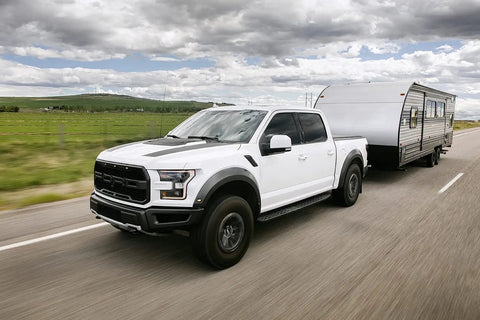 White truck towing a trailer on a highway using Weight Distribution Hitch With Tension Chain System For Easy Hitching And Anti Bounce Sway Control, 2 Inch Shank, Eight Inch Drop, 2 Five Sixteenths Inch Ball, 14K GTWR, Brackets Three To Six Inches, Tow Gear.