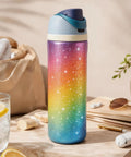 Colorful, glittery water bottle on a table with sunglasses and a drink nearby, showcasing outdoor lifestyle.