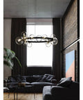 High Quality Top Shelf Modern Metal Chandelier With Clear Glass Bubbles And G9 Sockets hanging above a dark sofa in a stylish living room.