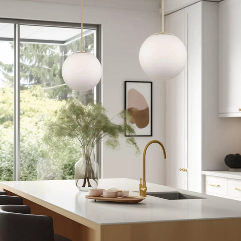 Ceres 14-Inch Mid Century Modern Globe Pendant Light With Frosted Glass Orb Warm Brass Finish in stylish kitchen setting.