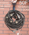 Beefy 50ft 12 Gauge Outdoor Extension Cord with eleven outlets coiled for storage against a brick wall.