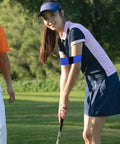 Woman wearing two pack golf swing arm bands elastic posture corrector and training aid for strength grip on golf course
