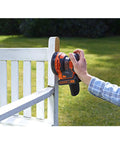 User operating Badass 18V Cordless Orbital Sander With Killer Dust Control on a wooden bench edge in sunlight.