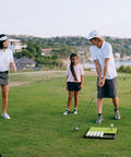 Family using Patented All In One Pro Grade Golf Practice Mat with Built In Ball Tray That Holds 32 Balls on a lush green field