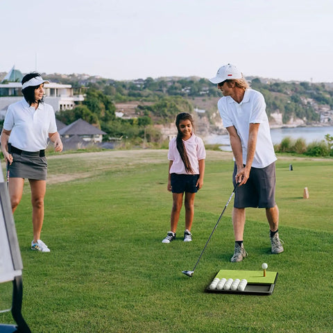 Family using Patented All In One Pro Grade Golf Practice Mat with Built In Ball Tray That Holds 32 Balls on a lush green field
