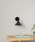 Two Pack Black Swing Arm Wall Sconces With Remote Control Cordless Battery Powered LED Wall Lamps on white wall above shelf.