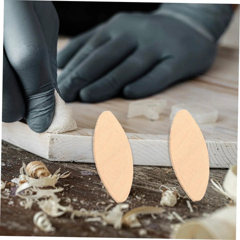 100 PC Wood Biscuits For Woodworking Pro Grade Slotting And Plywood Joinery Tool on wood surface with gloved hand detailing