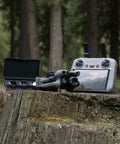 Mini 5 Pro Fly More Combo Plus With RC 2 Drone on log with controller, Ultra Light Pocket Sized Folding Quad in forest setting.