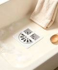 Hair Drain Stickers 100 Pcs Disposable Peel Stick placed in a sink with bubble bath, featuring a black mesh design.