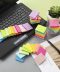 Small 1.5x2 Inch Sticky Notes, 50 Pads With 50 Sheets Each in 10 Bright Colors, scattered by laptop for home office use.