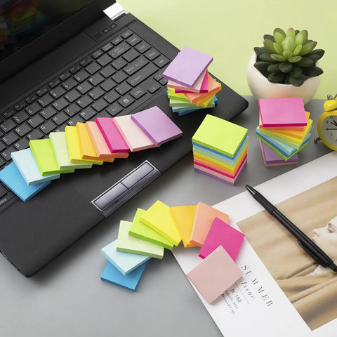 Small 1.5x2 Inch Sticky Notes, 50 Pads With 50 Sheets Each in 10 Bright Colors, scattered by laptop for home office use.
