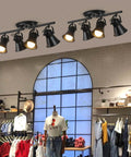 4 Light Track Lighting Kit in industrial black finish installed in clothing store, adjustable heads, ideal for various rooms.