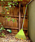 Lightweight Plastic Leaf Rake With 56 Inch Stainless Steel Handle And 22 Tines Plastic Head in a garden corner