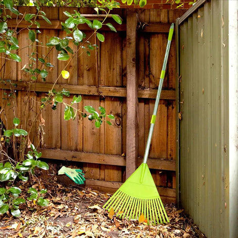 Lightweight Plastic Leaf Rake With 56 Inch Stainless Steel Handle And 22 Tines Plastic Head in a garden corner