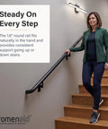 Woman holding Ultra Slick Satin Black 1.5ft ADA Handrail Kit on wooden stairs indoors.
