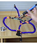 Third Hand Soldering Stand With Adjustable Metal Gooseneck Arms holding PCB on wooden table