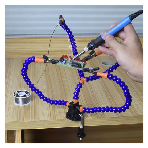 Third Hand Soldering Stand With Adjustable Metal Gooseneck Arms holding PCB on wooden table