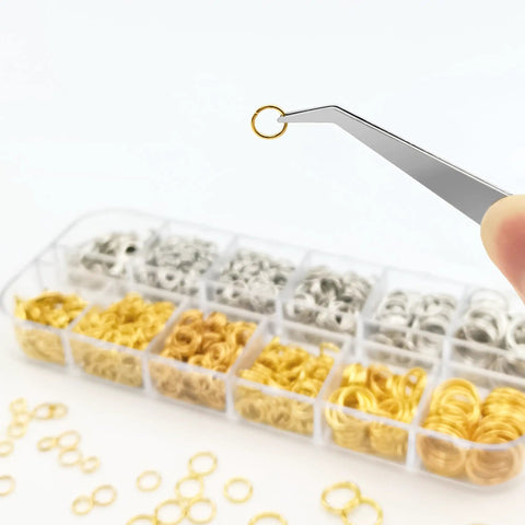 Tweezers holding a gold jump ring over a box of silver and gold assorted jump rings from DIY Jewelry Repair Kit With 1400 Pcs Assorted Jump Rings In Silver And Gold, Includes Pliers, Necklace Clasps, Tweezers And Opener For Quick Repairs, Crafting And Keychain Making Supplies.