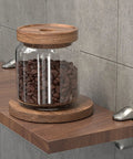 Adjustable Glass Shelf Bracket Wall Mount Made From Zinc Alloy Gold Finish Shelf Supports That Grips Tight For 3mm To 22mm Glass Panels Ideal For Home Decor Display Shelves And Storage supporting a wooden shelf with a jar of coffee beans.