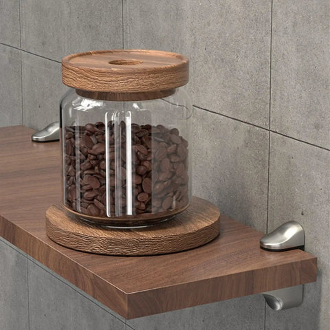 Adjustable Glass Shelf Bracket Wall Mount Made From Zinc Alloy Gold Finish Shelf Supports That Grips Tight For 3mm To 22mm Glass Panels Ideal For Home Decor Display Shelves And Storage supporting a wooden shelf with a jar of coffee beans.