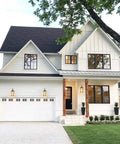 Modern farmhouse with outdoor wall lanterns enhancing the front porch, showing golden bronze exterior wall sconces with amber glass shade.