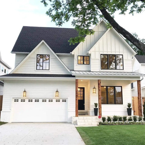 Modern farmhouse with outdoor wall lanterns enhancing the front porch, showing golden bronze exterior wall sconces with amber glass shade.