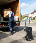 Industrial Grade Aluminum Alloy Hand Truck Featuring 500 Pound Heavy Duty Capacity For Tough As Nails Performance And Smooth Rolling Platform Dolly Cart With Extra Wide Base And Durable Construction next to a man loading boxes in a truck.