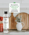 Food Grade Mineral Oil For Cutting Boards And Wood Conditioners Protectant For Bamboo Teak And Other Wood Kitchen Utensils, 8 oz bottle on counter with cutting boards and utensils.