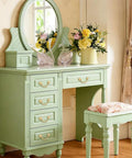 Vintage vanity table with mirror, adorned with flowers, and featuring classic bail cabinet pulls in gold, surrounded by elegant decor.