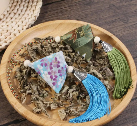 10 Pack Mugwort Triangle Sachets With Tassels Dragon Boat Festival Zongzi Shape Home Decor Bags Premium Cotton Fabric on a plate