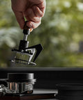 Heavy Duty Stainless Steel Espresso Distribution Tool 58Mm with nine precision needles, being held above an espresso basket.