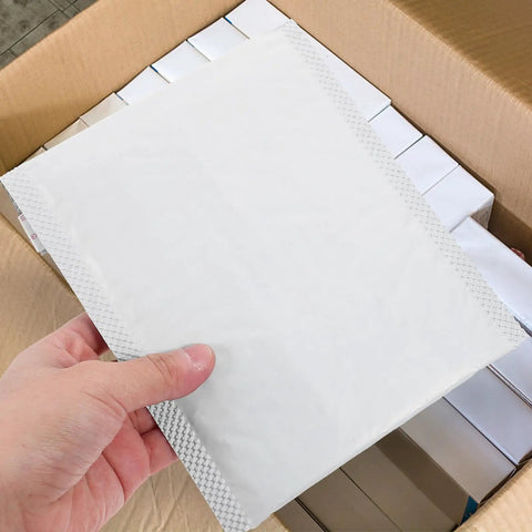 Hand holding a 100 Pack Bubble Envelope Mailers 15x18 Inches Plus 4cm Self Seal Waterproof Packaging Bag, box background