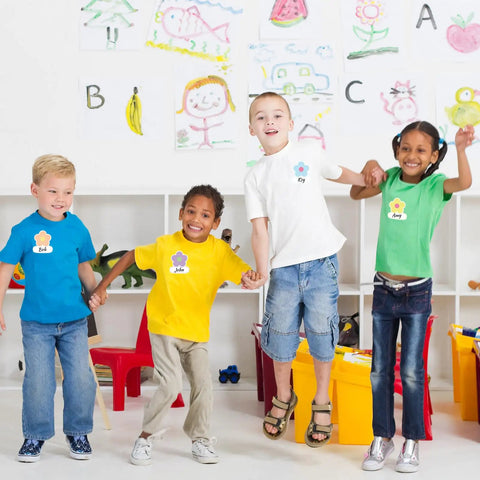 Children wearing 180 Pcs Flower Name Tag Stickers Set For Back To School in a classroom with colorful drawings.