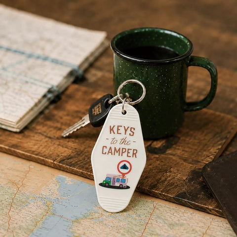 Four Piece Vintage Keychain Set For Camper RVs Retro Black And White Fobs Lightweight Durable Plastic Key Tags For The Fam Organization And Everyday Use shown next to a green mug and maps.