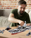 Man assembling 8 In 1 WW2 Aircraft Carrier Building Set With Helicopter And Boat Epic Naval Battleship Toy, 562 pieces.