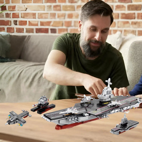 Man assembling 8 In 1 WW2 Aircraft Carrier Building Set With Helicopter And Boat Epic Naval Battleship Toy, 562 pieces.
