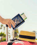 RFID Blocking Leather Passport Holder Travel Wallet For Women And Men, multi card organizer in use with suitcase and hat, dark blue.