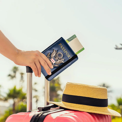 RFID Blocking Leather Passport Holder Travel Wallet For Women And Men, multi card organizer in use with suitcase and hat, dark blue.