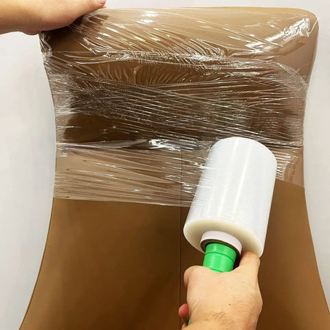 Person using 2-Pack Clear Stretch Wrap Film 80 Gauge 5.1 Inch By 1000 Feet With Plastic Handle For Pallet Wrapping on brown furniture