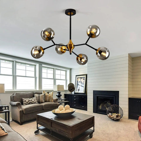 Six Light Glass Globe Chandelier With Adjustable Boom in gold and black, suspended in a modern living room setting with natural light.